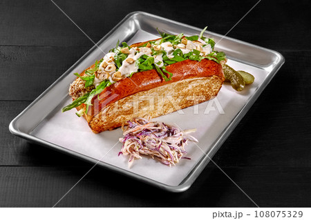 Sandwich in toasted brioche bread with chicken fingers, vegetables, mayo and cashews 108075329
