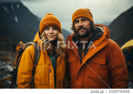 Portrait of happy couple in touristic outwear near the tent camp against the backdrop of picturesque mountain landscape. Caucasian family is engaged in a mountain hiking. Tourism and active lifestyle. 108076498