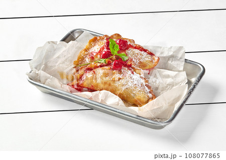 Puff pastry turnovers with cherry filling decorated with mint and powdered sugar Puff pastry turnovers with cherry filling decorated with mint and powdered sugar 108077865