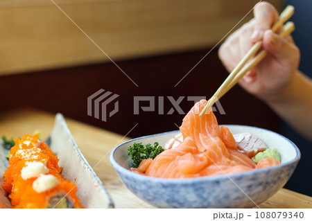 Asian woman eating salmon slice sashimi with rice in Japanese restaurant 108079340