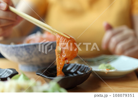 Salmon sashimi in chopsticks dipping with soy sauce 108079351