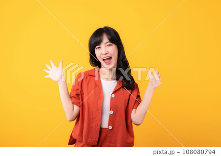Portrait young beautiful asian woman happy smile dressed in orange clothes showing fist up hand gesture isolated on yellow studio background. Successful hooray celebrate young person concept. Portrait young beautiful asian woman happy smile dressed in orange clothes showing fist up hand gesture isolated on yellow studio background. Successful hooray celebrate young person concept. 108080794