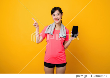 Portrait young asian sports fitness woman happy smile wearing pink sportswear and smartphone doing exercise training workout against yellow studio background. technology wellness lifestyle concept. Portrait young asian sports fitness woman happy smile wearing pink sportswear and smartphone doing exercise training workout against yellow studio background. technology wellness lifestyle concept. 108080865