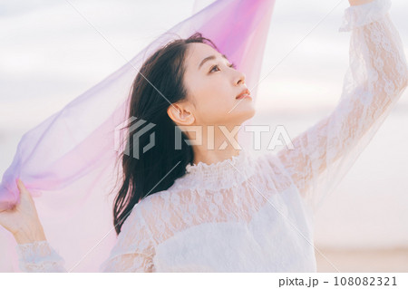 夕日背景の女性ポートレート 108082321