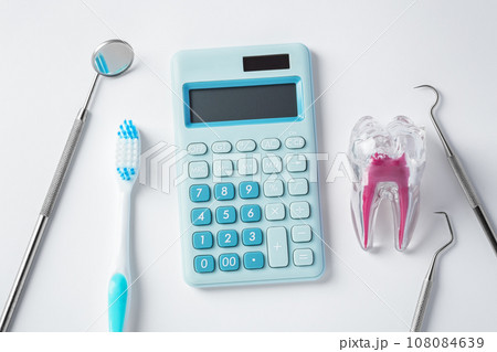 Dental tools with blue calculator and tooth on white background, top view 108084639