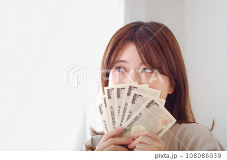 笑顔で嬉しそうにお金を持つ若い女性 笑顔で嬉しそうにお金を持つ若い女性 108086039