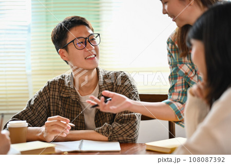 Young creative team discussing new business opportunity and sharing ideas while working together in office Young creative team discussing new business opportunity and sharing ideas while working together in office 108087392