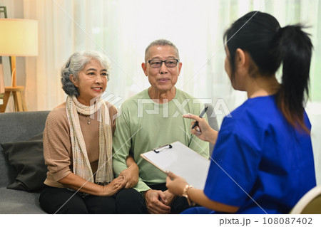 Smiling senior couple listening attentively to nurse or general practitioner explaining therapy details during home visit Smiling senior couple listening attentively to nurse or general practitioner explaining therapy details during home visit 108087402