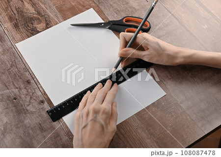hands of an elderly woman fold origami paper. Creating an origami paper crane 108087478