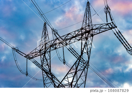 Silhouette of a high voltage tower with the clouds at sunset on a background 108087829