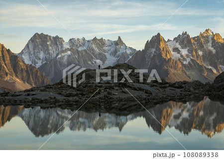 Silhouette of Hiker, Mountains and Reflection in Lac Blanc Lake at Sunset. Golden Hour. French Alps 108089338