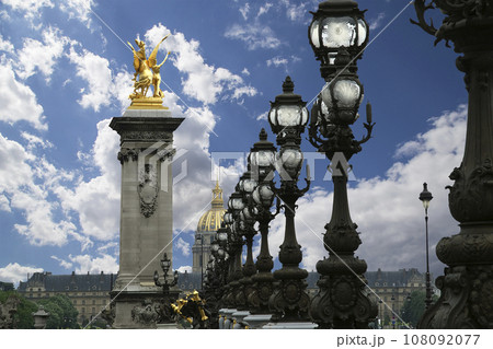 Lamp posts on Alexander III Bridge against the background of a beautiful sky with clouds. Paris, France. This arch bridge is one of the most beautiful river crossings in the world Lamp posts on Alexander III Bridge against the background of a beautiful sky with clouds. Paris, France. This arch bridge is one of the most beautiful river crossings in the world 108092077