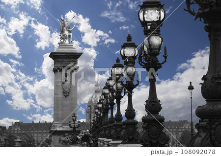 Lamp posts on Alexander III Bridge against the background of a beautiful sky with clouds. Paris, France. This arch bridge is one of the most beautiful river crossings in the world Lamp posts on Alexander III Bridge against the background of a beautiful sky with clouds. Paris, France. This arch bridge is one of the most beautiful river crossings in the world 108092078