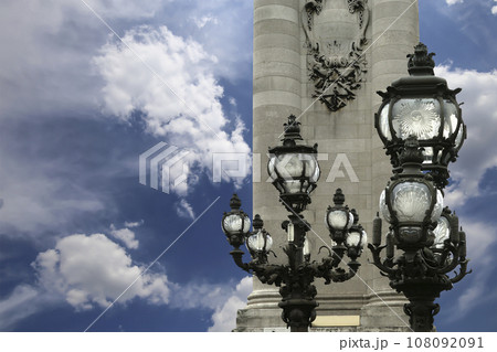 Lamp posts on Alexander III Bridge against the background of a beautiful sky with clouds. Paris, France. This arch bridge is one of the most beautiful river crossings in the world Lamp posts on Alexander III Bridge against the background of a beautiful sky with clouds. Paris, France. This arch bridge is one of the most beautiful river crossings in the world 108092091