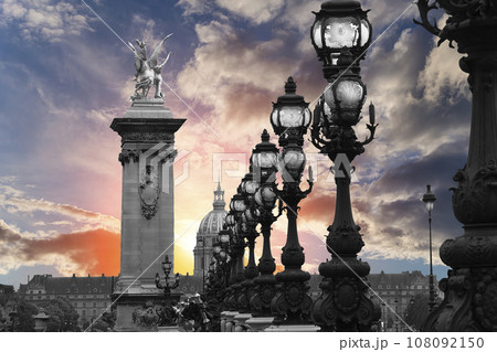 Lamp posts on Alexander III Bridge against the background of a beautiful sky at sunset. Paris, France. This arch bridge is one of the most beautiful river crossings in the world 108092150