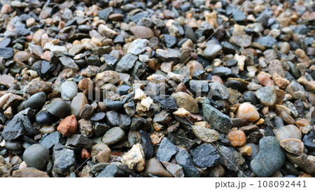 wet gravel close-up blurred along the edge of the picture, gray crushed rock mineral interspersed with various rocks, pebble texture wallpaper full frame, crushed stone as a building material 108092441