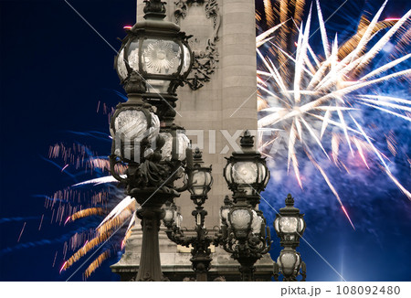 Celebratory colorful fireworks over the Lamp posts on Alexander III Bridge. Paris, France. This arch bridge is one of the most beautiful river crossings in the world 108092480