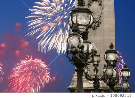 Celebratory colorful fireworks over the Lamp posts on Alexander III Bridge. Paris, France. This arch bridge is one of the most beautiful river crossings in the world 108092515