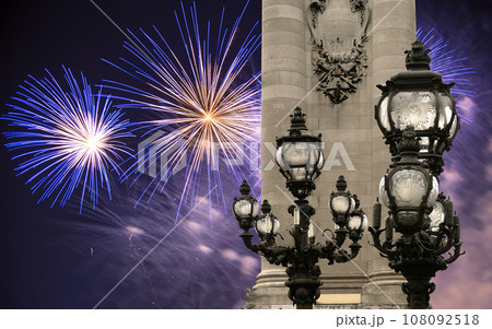Celebratory colorful fireworks over the Lamp posts on Alexander III Bridge. Paris, France. This arch bridge is one of the most beautiful river crossings in the world 108092518