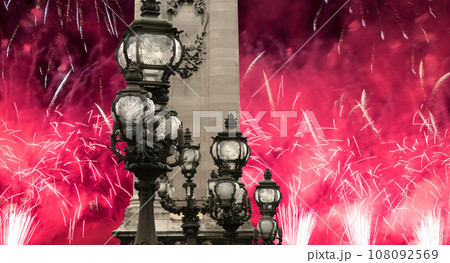 Celebratory colorful fireworks over the Lamp posts on Alexander III Bridge. Paris, France. This arch bridge is one of the most beautiful river crossings in the world 108092569