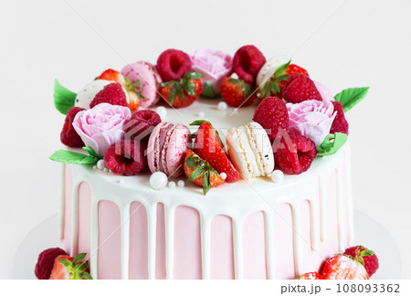 Beautiful pink cake decorated with macarons, raspberries, strawberries and sugar rose flowers. 108093362