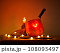 Halloween pumpkin with a comically carved face sits on a table, atmosphere is enhanced by warm 108093497