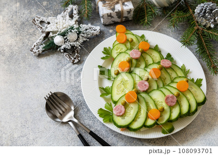 Christmas tree from a salad olivier on a gray stone background. Christmas appetizer. Copy space. Christmas tree from a salad olivier on a gray stone background. Christmas appetizer. Copy space. 108093701