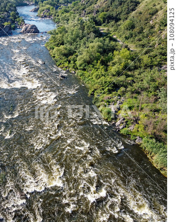 Picturesque river rapids on the Southern Bug. Rapid flow of the river over rocky terrain, landscape from a bird's eye view. Picturesque river rapids on the Southern Bug. Rapid flow of the river over rocky terrain, landscape from a bird's eye view. 108094125