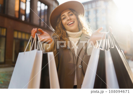 Smiling woman after shopping on city street. Purchases, sale concept. Online shopping concept. Smiling woman after shopping on city street. Purchases, sale concept. Online shopping concept. 108094671