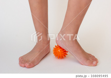 Cropped child legs doing exercises with spiky needle ball  108095495
