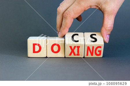Docs or doxing symbol. Concept words Docs Doxing on wooden block. Beautiful grey table grey background. Businessman hand. Business docs or doxing concept. Copy space. 108095629