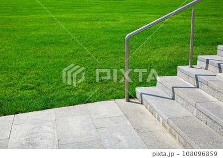 granite sidewalk with stone stairs and steel railings along a green lawn on a sunny summer day, a landscaped park for walking, nobody. granite sidewalk with stone stairs and steel railings along a green lawn on a sunny summer day, a landscaped park for walking, nobody. 108096859