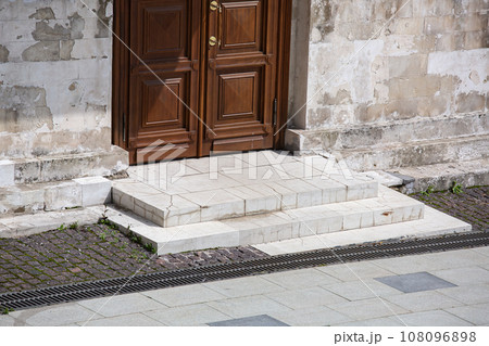 brown wooden entrance door of an white old stone building on a sunny day, close-up architecture of the old city, nobody. 108096898