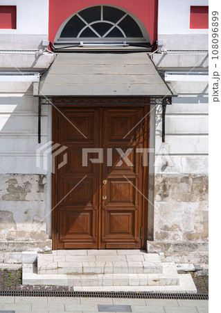 wooden entrance door of an old stone building with shabby walls on a sunny day, architecture of the old city, nobody. wooden entrance door of an old stone building with shabby walls on a sunny day, architecture of the old city, nobody. 108096899