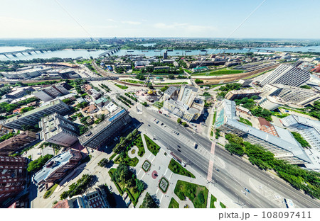 Aerial city view with crossroads and roads, houses, buildings, parks and parking lots. Sunny summer panoramic image 108097411