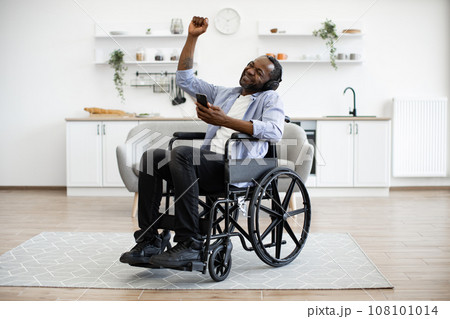 Adult in wheelchair dancing while hearing tunes in headphones during break 108101014