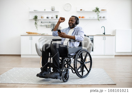 Adult in wheelchair dancing while hearing tunes in headphones during break 108101021