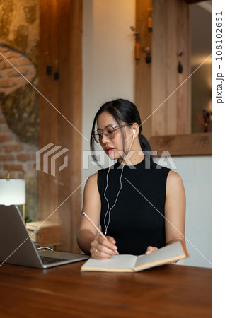 A focused Asian businesswoman is having an online meeting or studying online while sitting in a cafe A focused Asian businesswoman is having an online meeting or studying online while sitting in a cafe 108102651