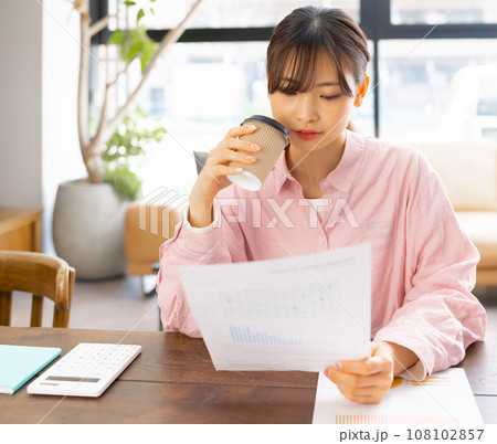 リビングでコーヒーを飲みながらテレワークの女性 108102857
