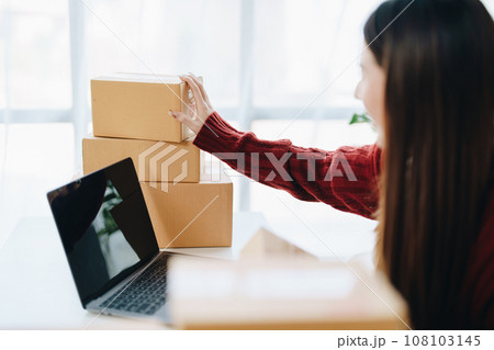 Asian female business owner handles delivery of orders to customers. 108103145