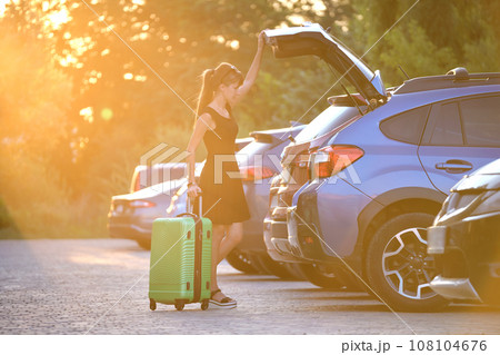 Young female driver taking out luggage suitcase bag out of her car. Travelling and vacations concept Young female driver taking out luggage suitcase bag out of her car. Travelling and vacations concept 108104676