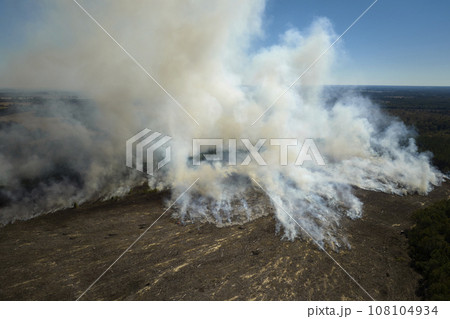 View from above of dense smoke from woodland and field on fire rising up polluting air. Concept of natural disaster View from above of dense smoke from woodland and field on fire rising up polluting air. Concept of natural disaster 108104934