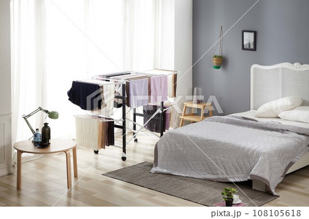 Laundry drying rack,  white pillow on bed 108105618