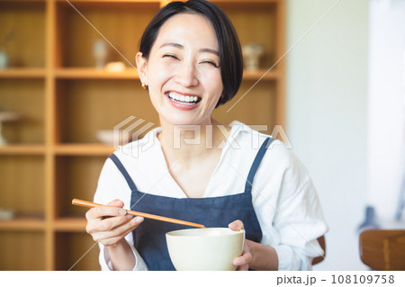 食事をするエプロン姿の若い女性 108109758