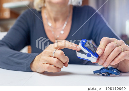 Woman is inserting finger into electronic pulse oximeter. 108110060