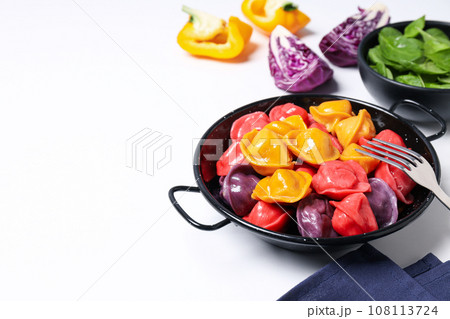 Colored dumplings in frying pan and vegetables on white background, space for text Colored dumplings in frying pan and vegetables on white background, space for text 108113724