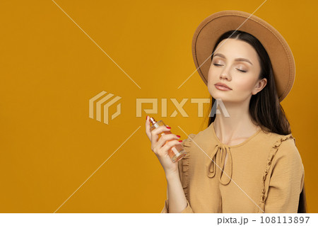 Attractive girl in a hat with perfume in her hand Attractive girl in a hat with perfume in her hand 108113897