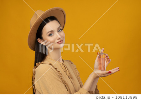 Attractive girl in a hat with perfume in her hand Attractive girl in a hat with perfume in her hand 108113898
