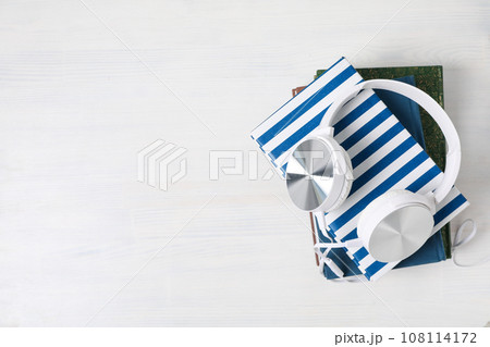 Headphones on books on white wooden background, space for text 108114172
