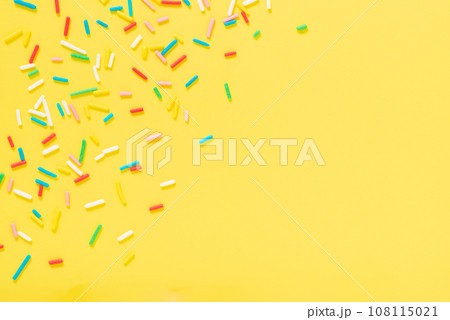 flat lay colorful sprinkles over yellow background 108115021